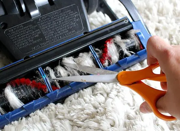 Hair clogged around the brush roll with safety precaution to clean it regularly to empty the tool's extra dirt.