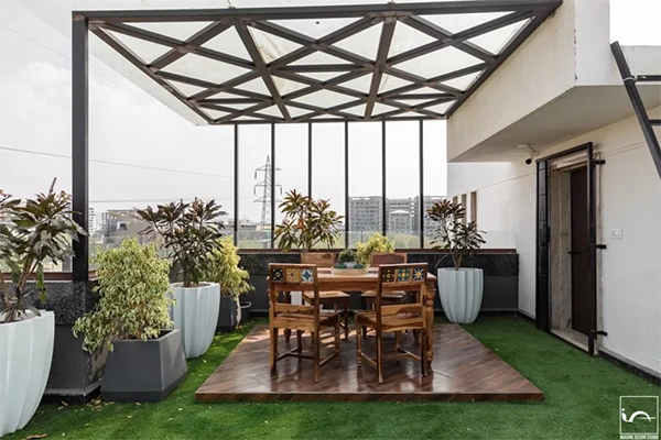 Living room with sliding glass doors opening onto a shaded terrace, outdoor seating and garden planting