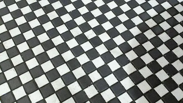 Small checkerboard mosaics hide footprints and forgive minor floor irregularities. 